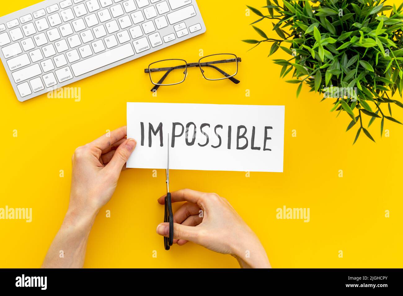 Hands cutting card with text Impossible into Possible. Motivation ...