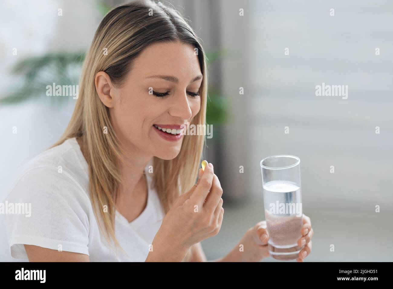 Smiling pretty woman taking pill after waking up, copy space Stock Photo