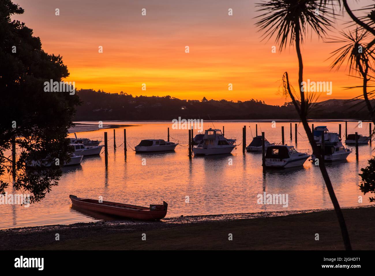 Pleasure cruisers and a Maori Waka (war canoe) moored in the bay at Waitangi at sunset, Bay of Islands, north island, New Zealand Stock Photo