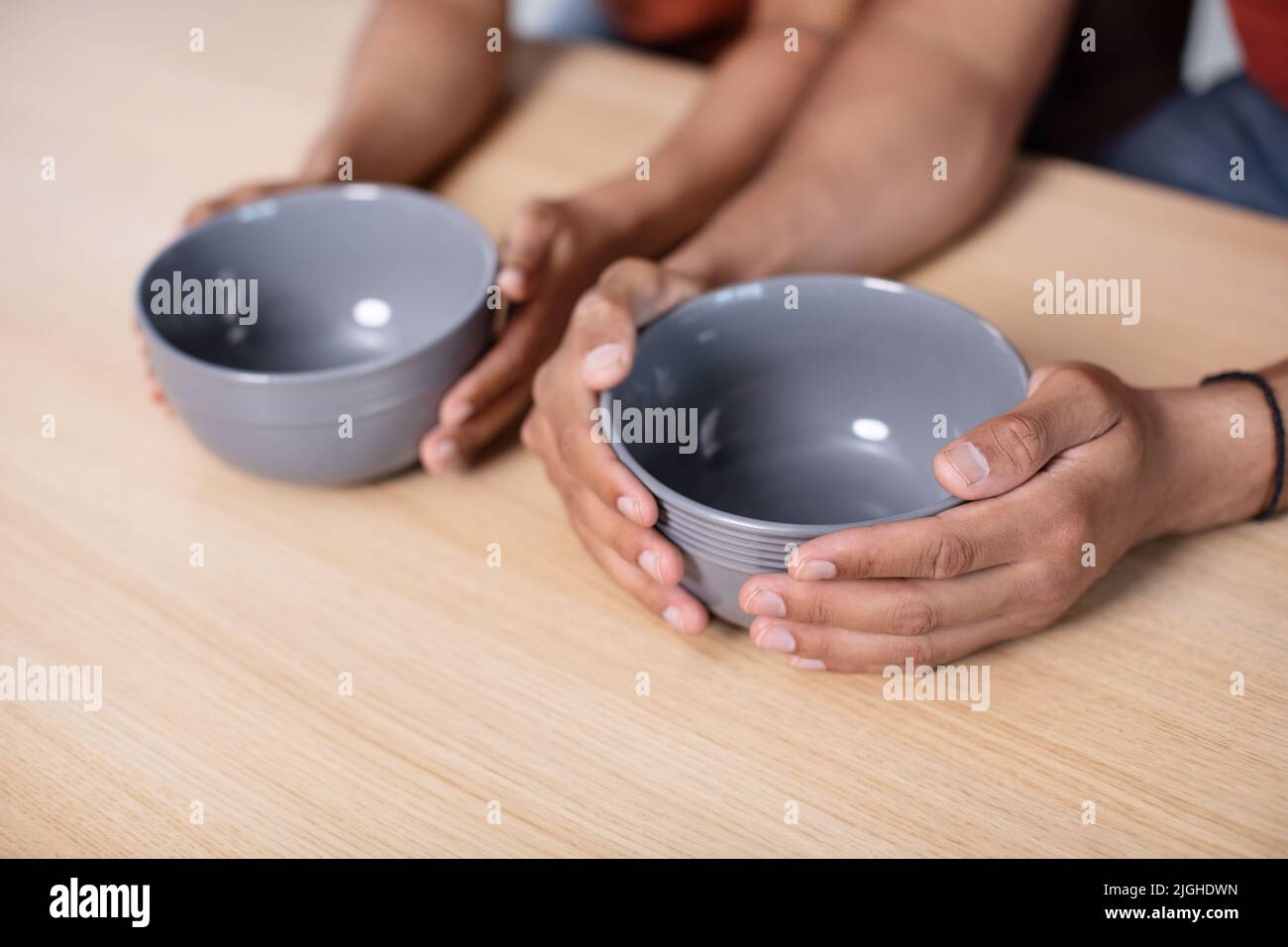 Hands of hungry young african american wife and husband holding empty plates on table in kitchen Stock Photo