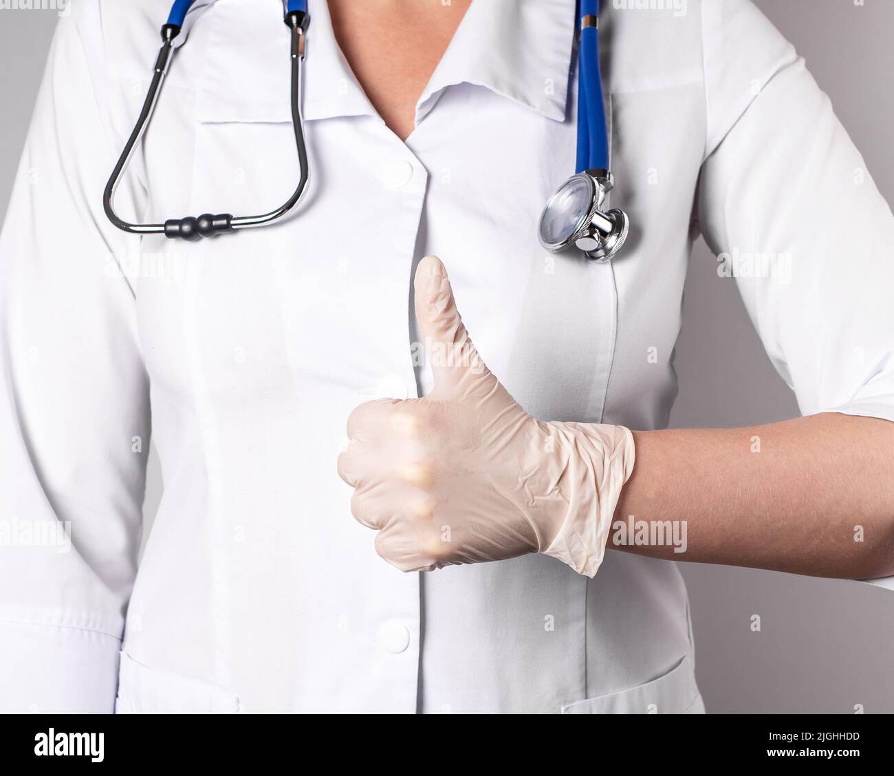 Doctor with thumb up gesture. Good health, medical professional competence, confidence concept. Woman in lab coat and in gloves showing no problems to patient. High quality photo Stock Photo