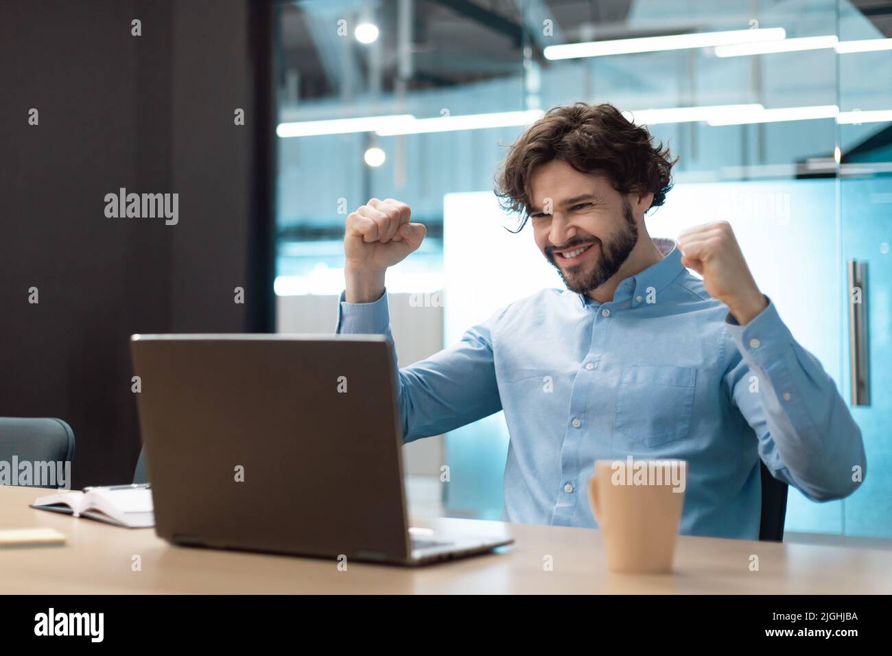 Excited mature businessman celebrating achievement, making great deal or agreement, gesturing YES near laptop at office Stock Photo