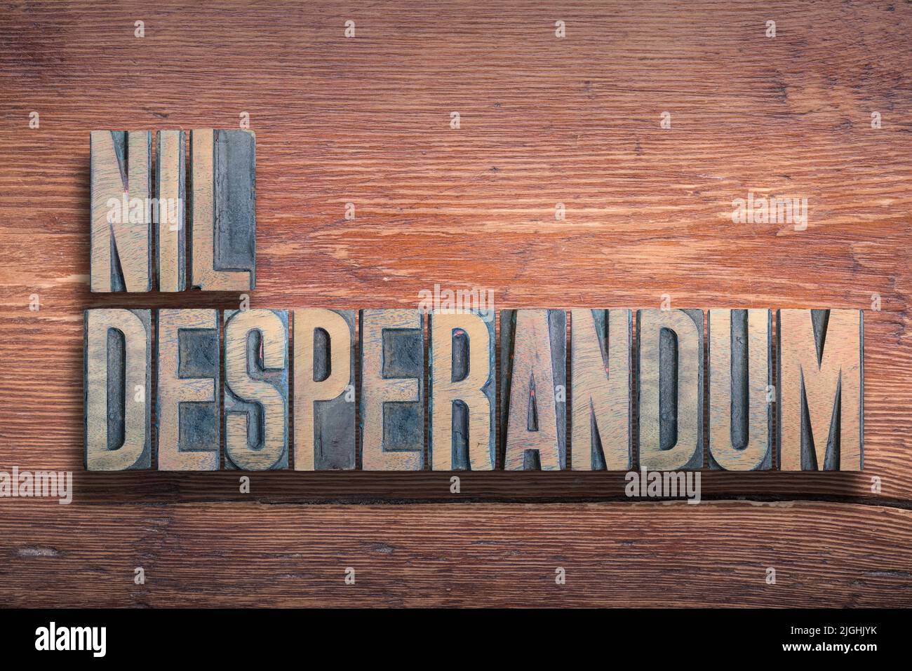 Nil desperandum ancient Latin saying meaning - Never despair, combined on vintage varnished wooden surface Stock Photo