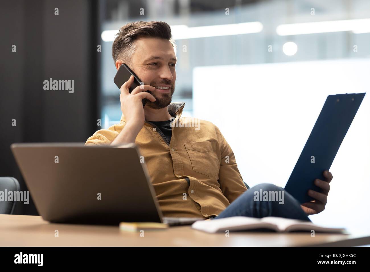 Entrepreneur Man Talking On Phone Holding File Binder In Office Stock Photo