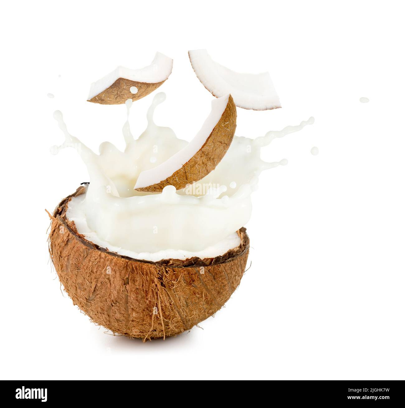 coconut milk and pieces spilling out half nut Stock Photo