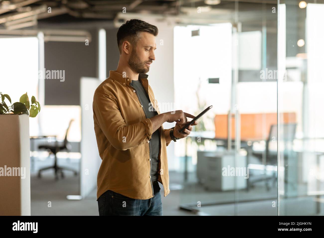 Male Entrepreneur Using Digital Tablet Working Standing In Modern Office Stock Photo
