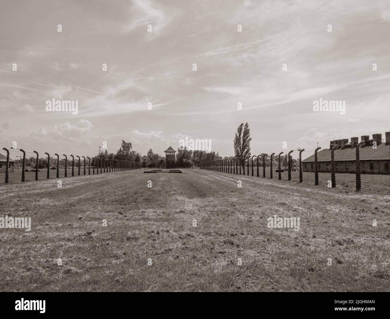 Oświęcim, Poland - June 05, 2019: Electric fence with barbed wire and watchtower at the Auschwitz-Birkenau concentration camp in Oświęcim, Poland. Eur Stock Photo