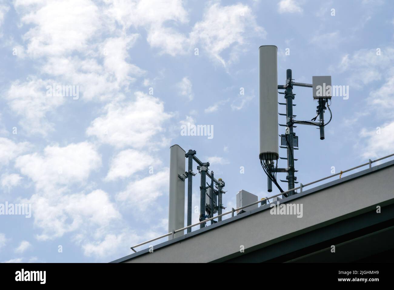 Multiple antenna on the rooftop of a house with scattered clouds in background 5G 4G LTE Stock Photo