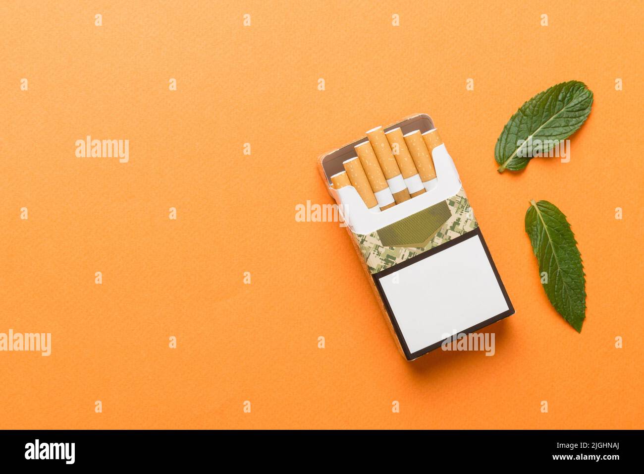 Pack of menthol cigarettes and fresh mint on colored table, Menthol