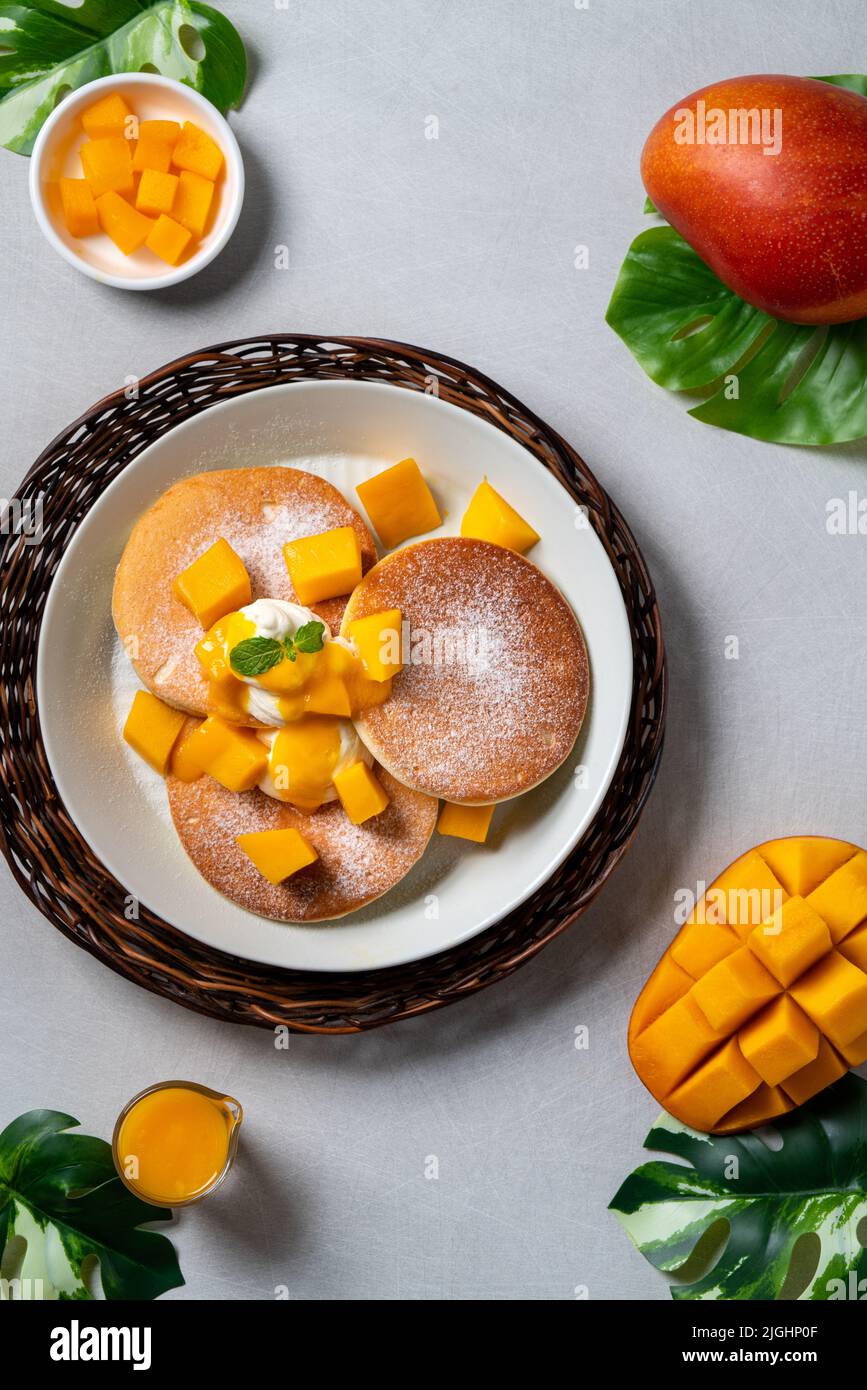 Delicious Japanese souffle pancake with dice mango fruit pulps and jam on white table background. Stock Photo