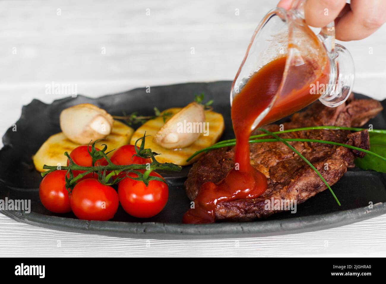 Pouring steak with ketchup, meat and garnish meal Stock Photo Alamy