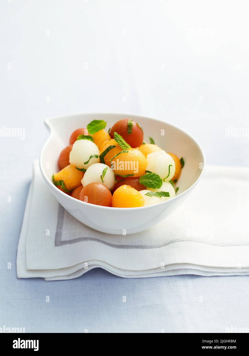 Melon balls served in bowl with mint leaves Stock Photo