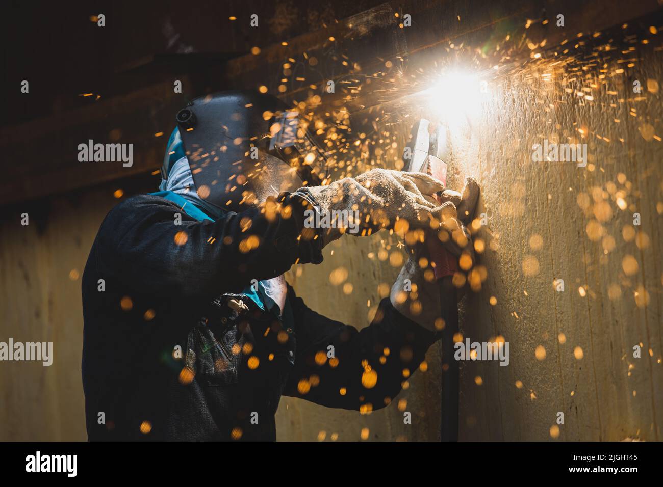 Male  worker wearing protective clothing and repair welding spark shell plate industrial construction oil and gas or  storage tank inside confined spa Stock Photo