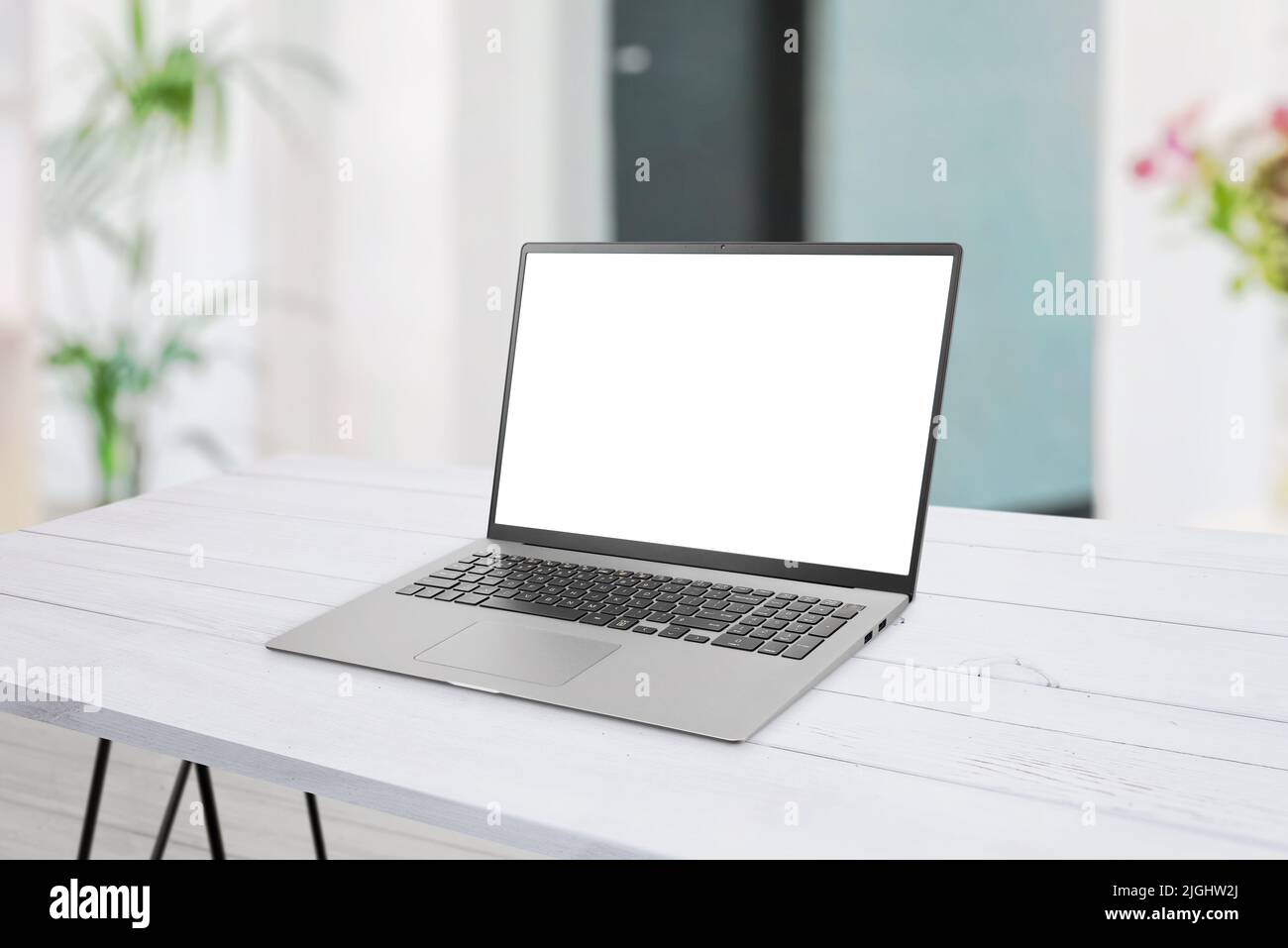 Laptop mockup on desk. Clean flat composition. Isolated display for web page mockup. Living room interior in background Stock Photo