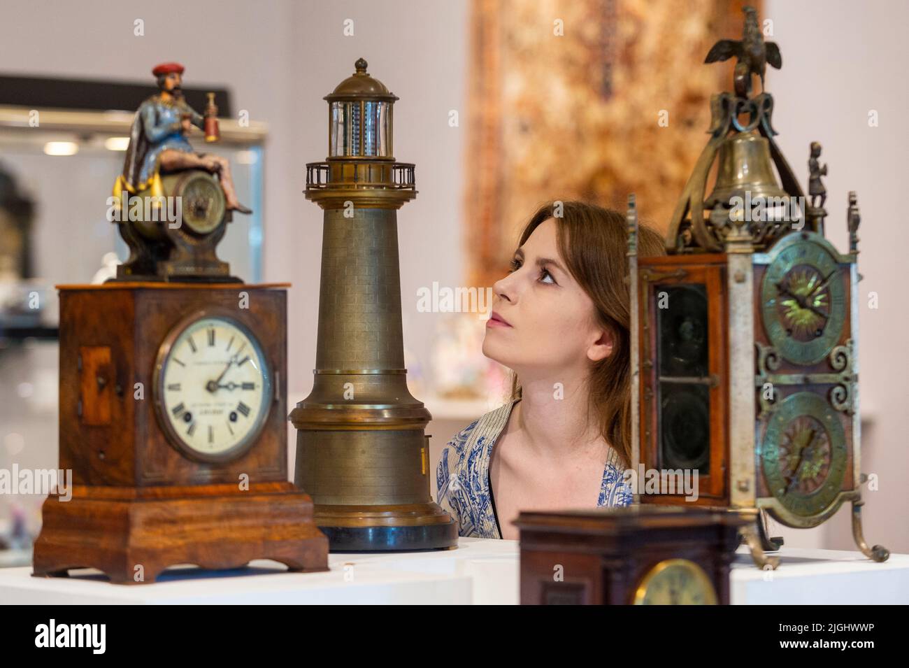 London, UK.  11 July 2022. A staff member views (C) 'A good and rare late 19th century French automata lighthouse timepiece' by Guilmet (Est. £3,000 - £4,000) at a preview of Bonhams’ Fine Clocks sale at their New Bond Street gallery. The lots will be auctioned on 14 July.  Credit: Stephen Chung / Alamy Live News Stock Photo