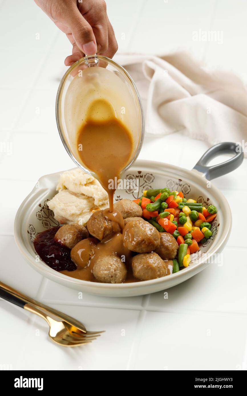 Delicious Homemade Swedish Meatballs Kottbullar with Mushroom Cream Sauce, Boiled Mix Vegetable, and Lingonberry Jam, Pour Mushroom Sauce Stock Photo