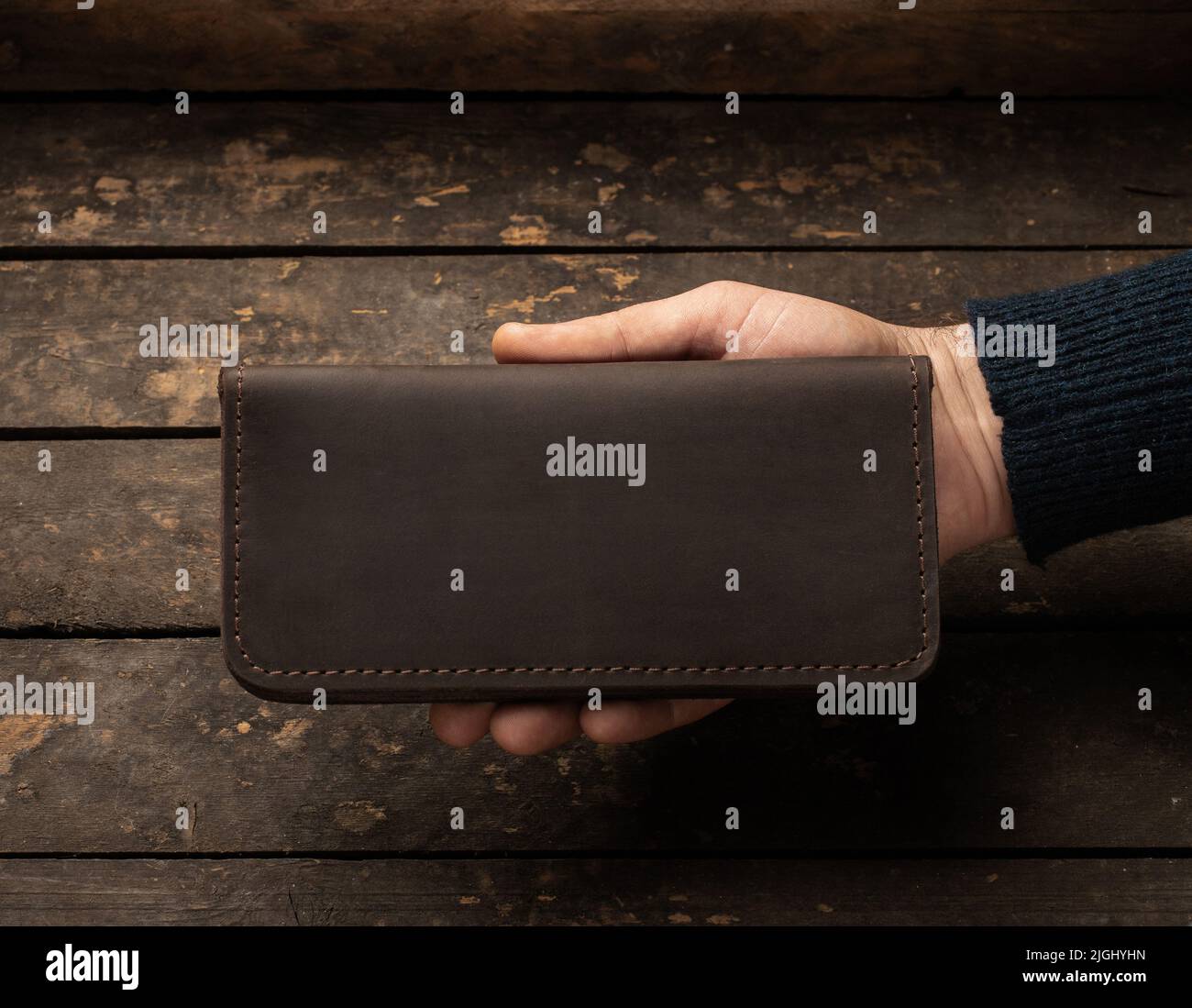 Leather men's wallet in a man's hand on a vintage wooden background. Flat lay. Place for text. Copyspace Stock Photo