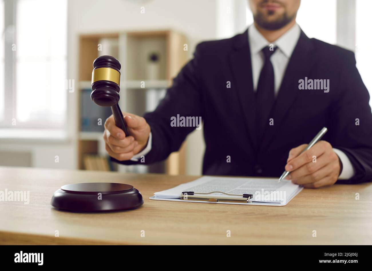Serious male judge in his office pass verdict hitting judge's gavel on sound block. Stock Photo