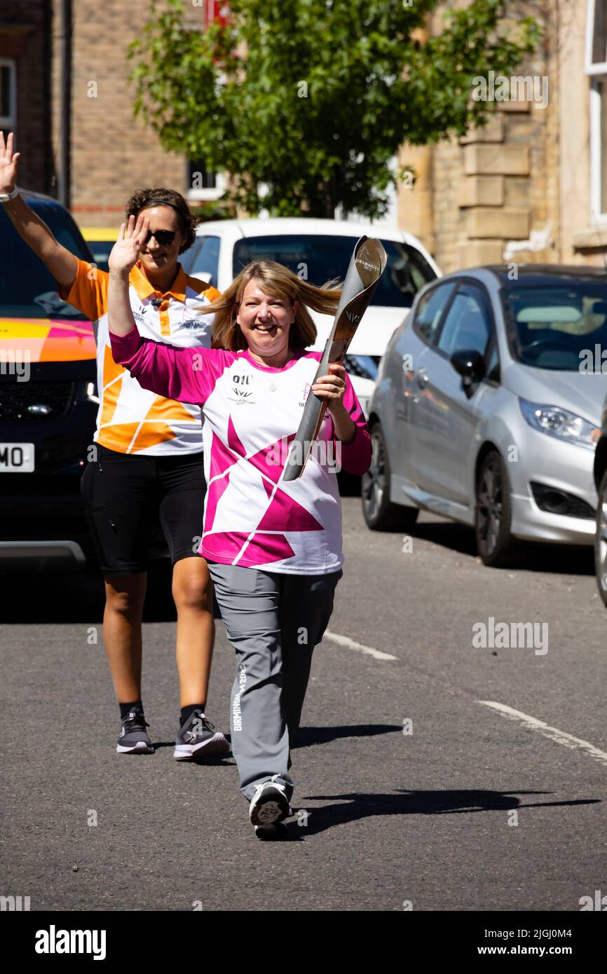 The Friendly Bench founder, Lyndsey Young carries the Queens Baton along Avenue road, Grantham, Lincolnshire, England. The Baton is en route to the 16 Stock Photo