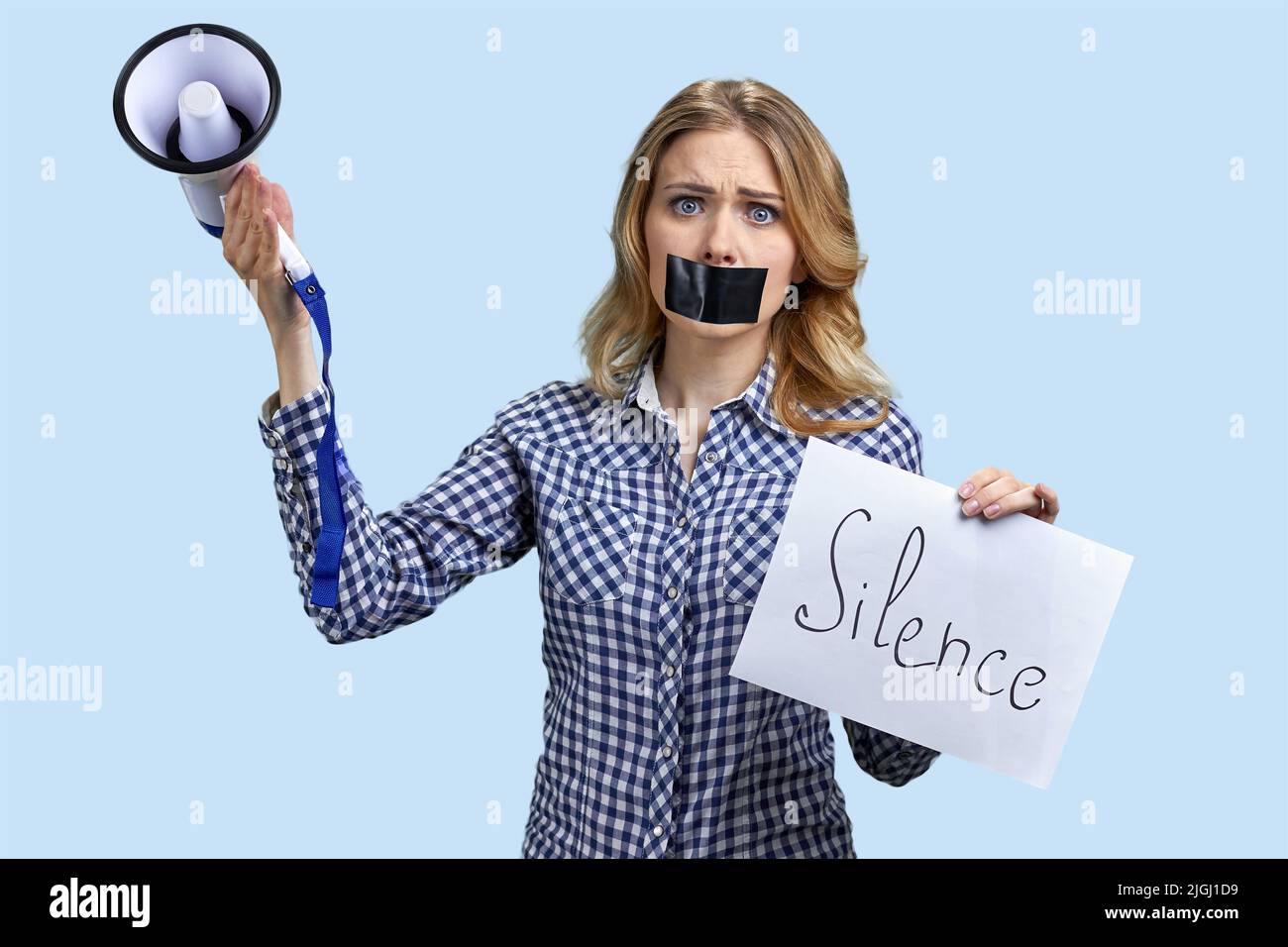 Woman protester with taped mouth holding banner with inscription Silence. Free speech concept. Stock Photo