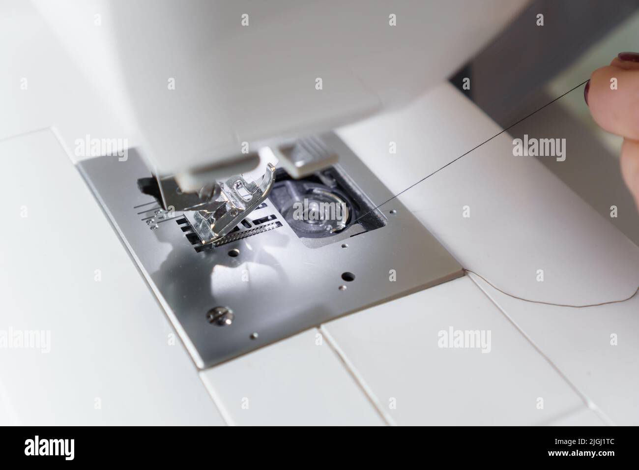 Seamstress prepare sewing machine. Tailor puts needle and spool of