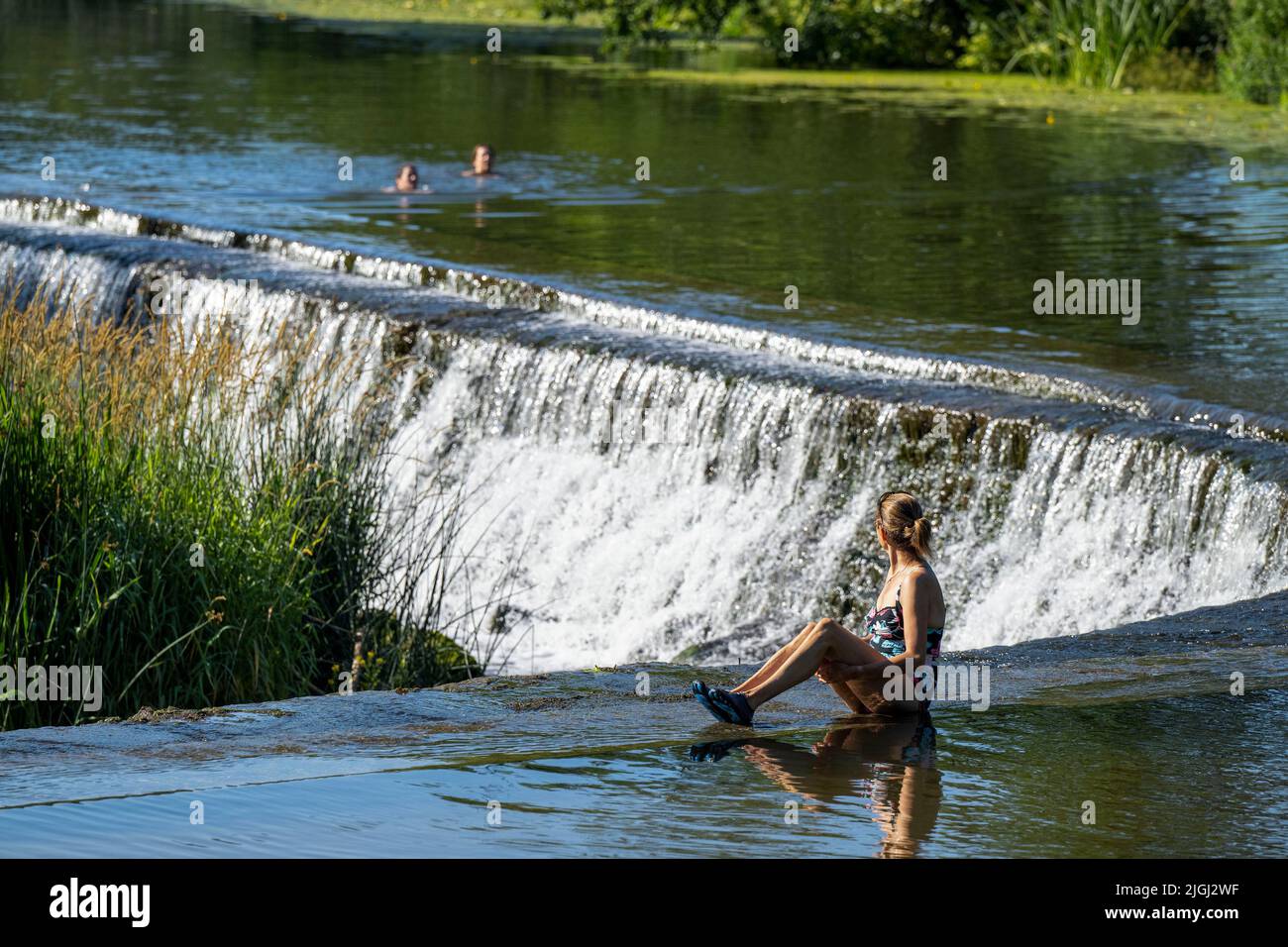 People cool off in the river Avon at Warleigh Weir near Bath in Somerset as temperatures continue to soar across the United Kingdom. Stock Photo