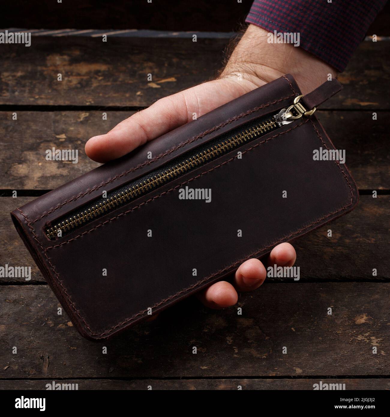 Leather brown men's wallet in a man's hand on a vintage wooden background. Flat lay. Place for text. Copyspace Stock Photo