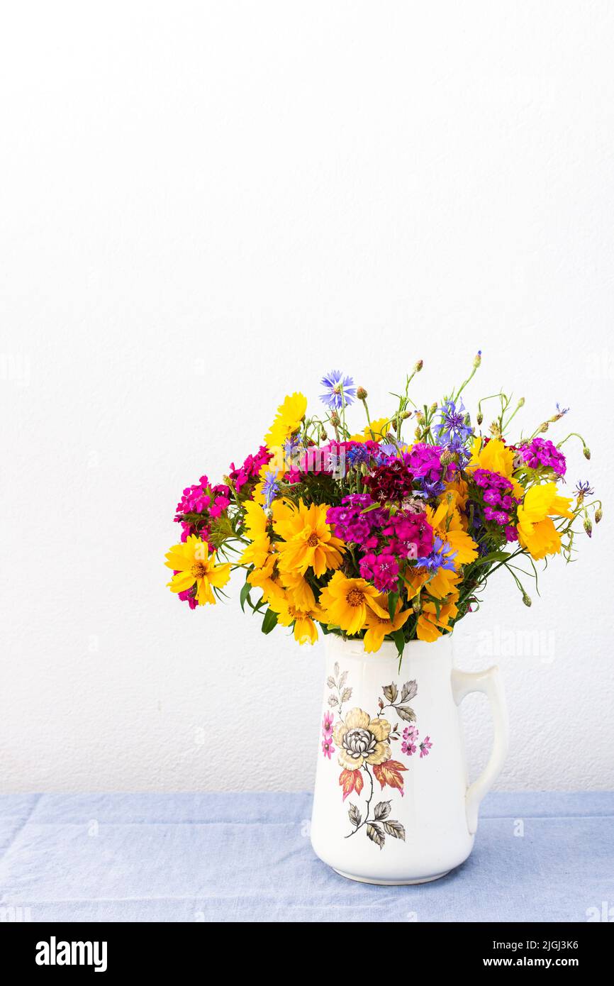 Beautiful summer bouquet of carnations, cornflowers and yellow chamomiles, part of home interior Stock Photo