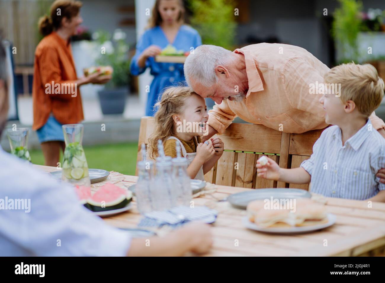 Multi generation family having garden party celebration, grandfather is entertaining grandchildren, laughing and having fun. Stock Photo