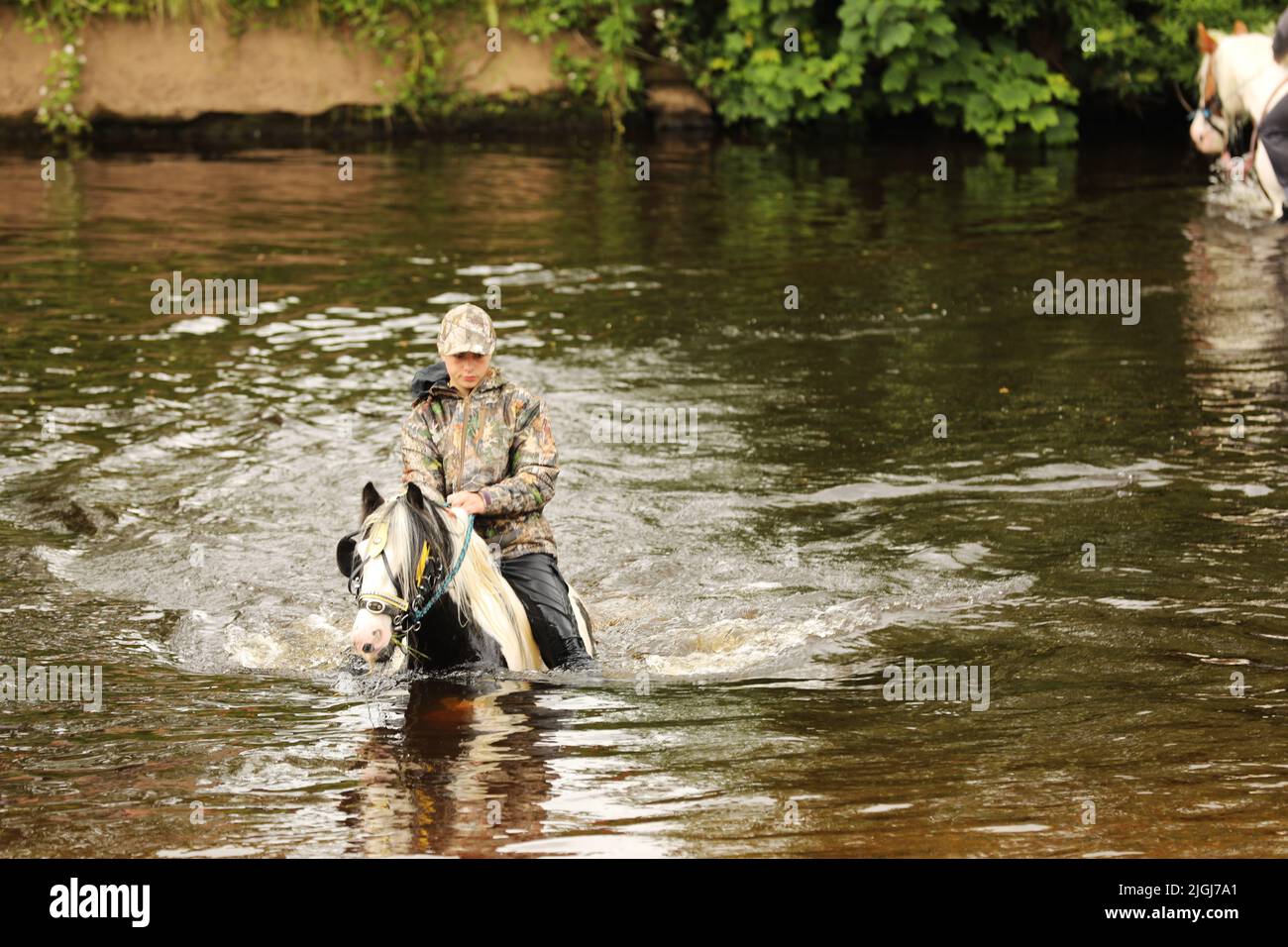A teenage boy riding his horse through the River Eden, Appleby Horse Fair, Appleby in Westmorland, Cumbria Stock Photo