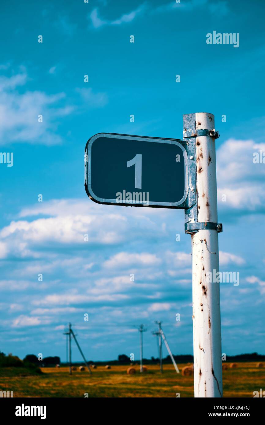 One kilometer road sign against a blue sky with white clouds Stock Photo