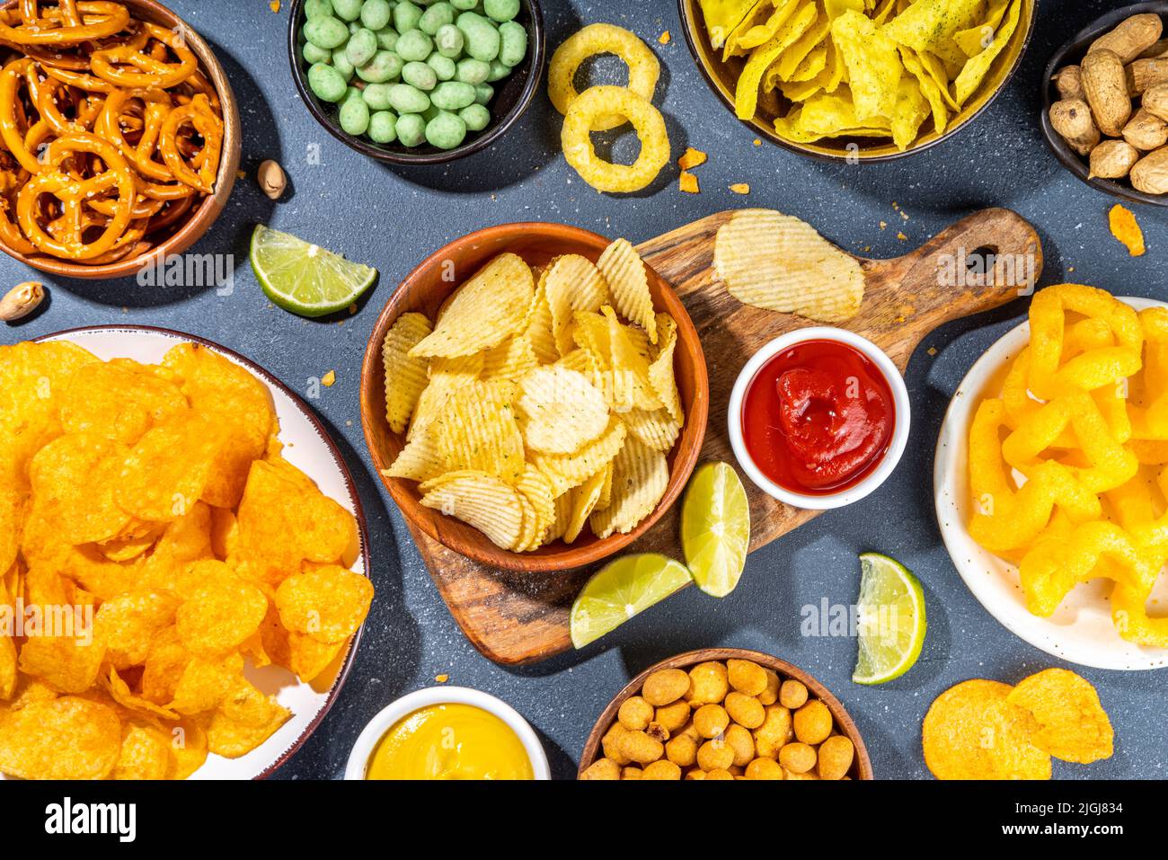 Various unhealthy salty bar snacks set. Dark grey table background with