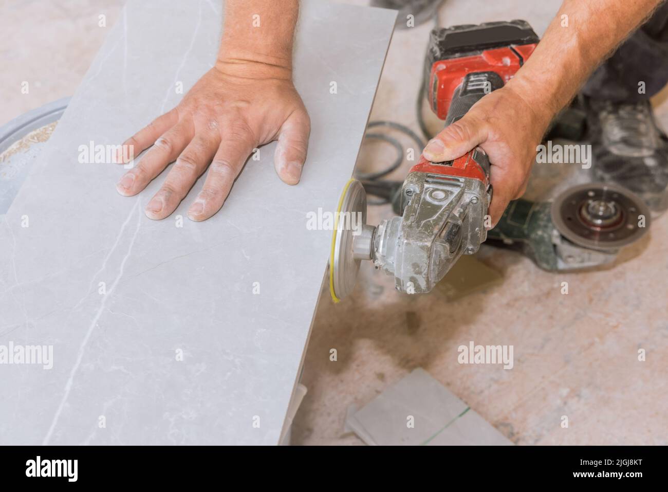 Worker polishing corner tiles on angle grinder using diamond grinding