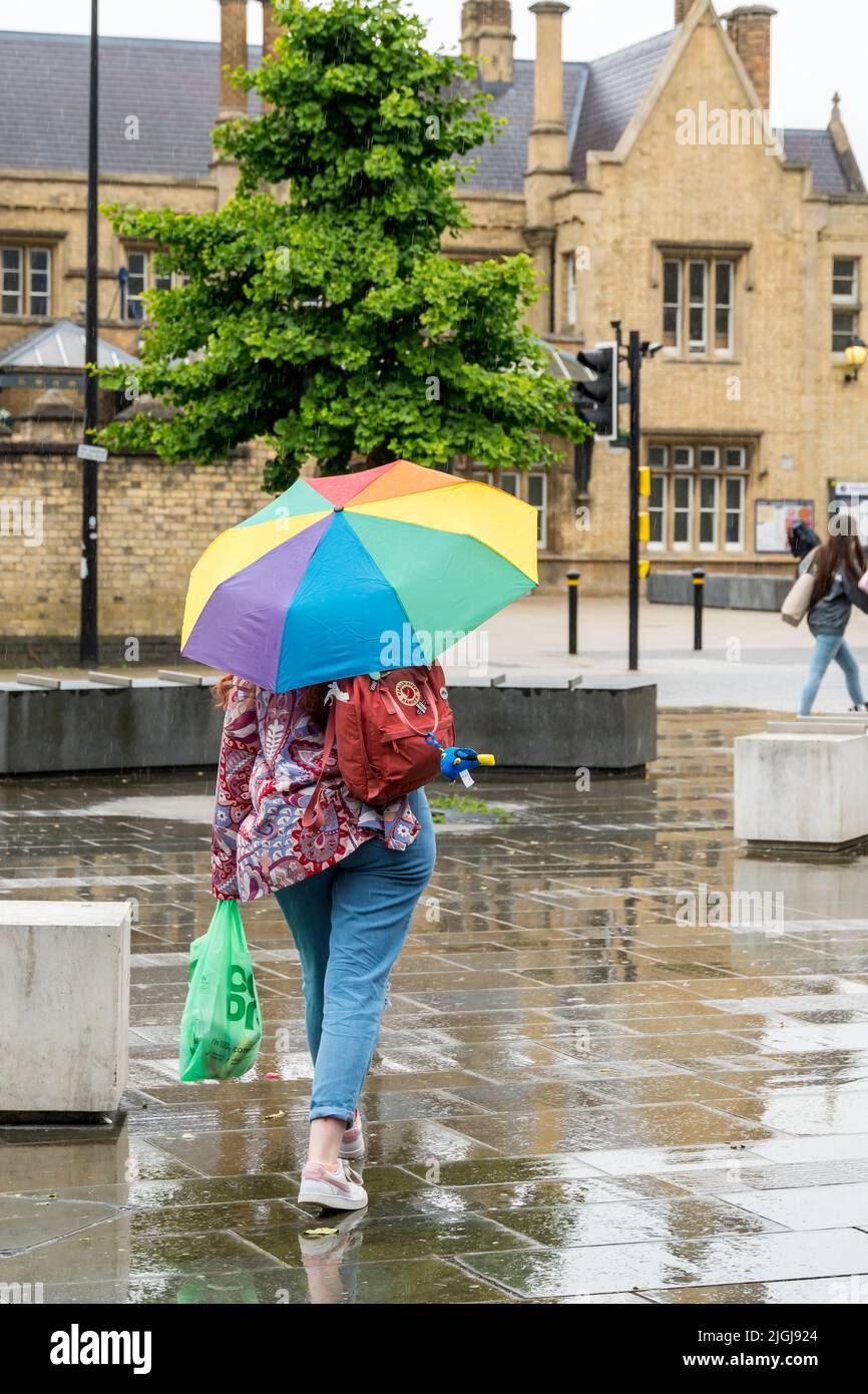 Lady carrying open multi coloured umbrella in downpour St Marys street Lincoln city 2022 Stock Photo