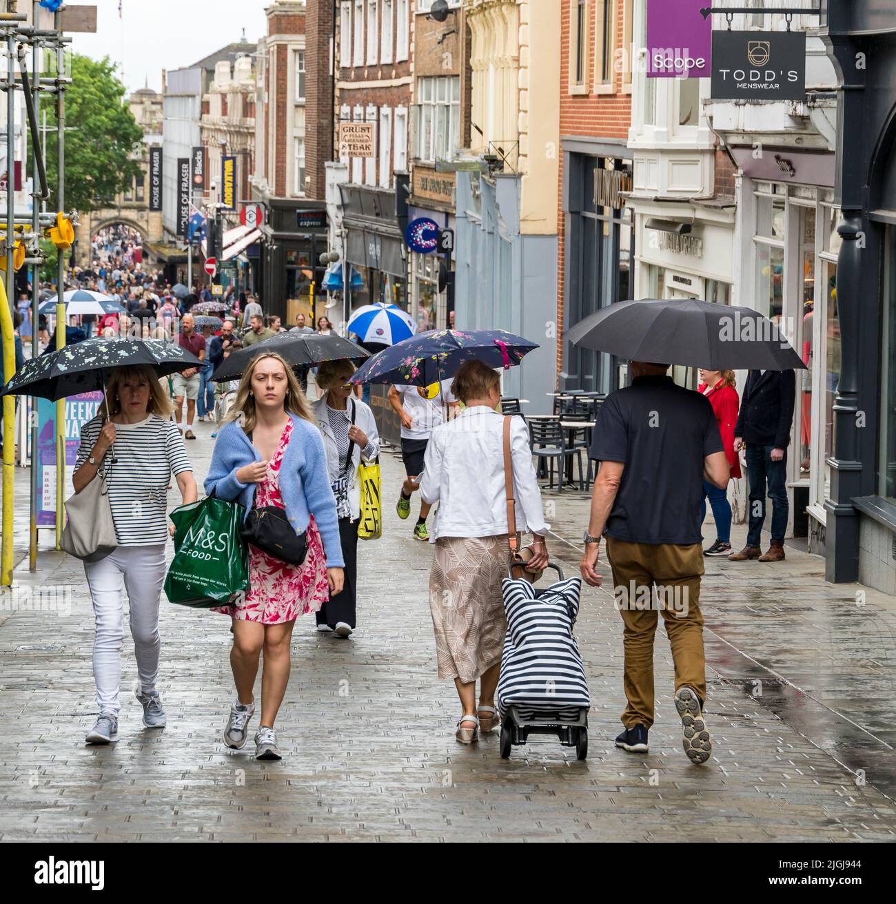 Pedestrians carrying open umbrellas during rain storm High Street Lincoln city 2022 Stock Photo