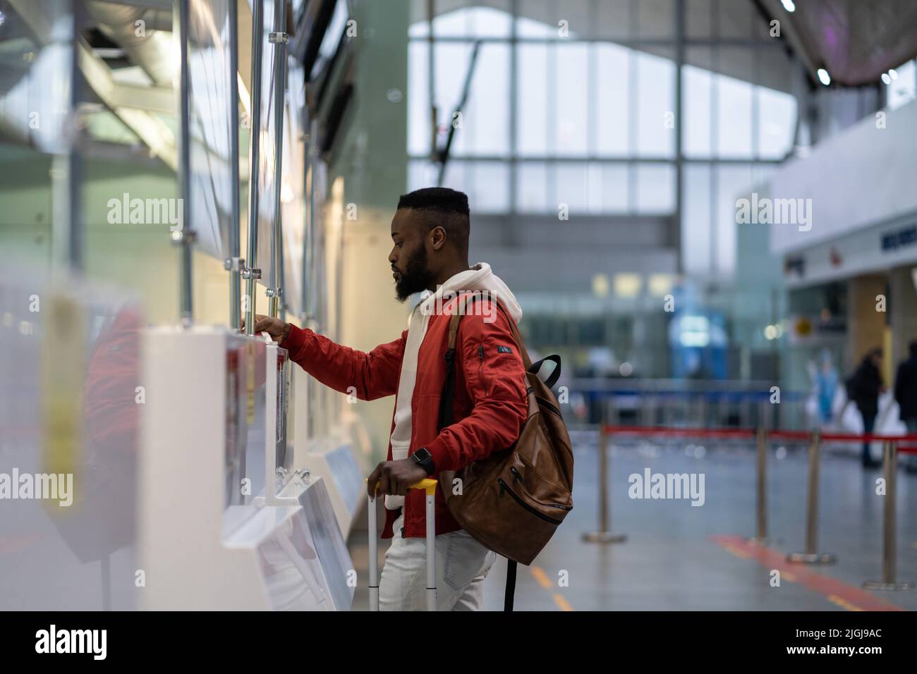 African young man traveler showing documents at check-in counter in ...