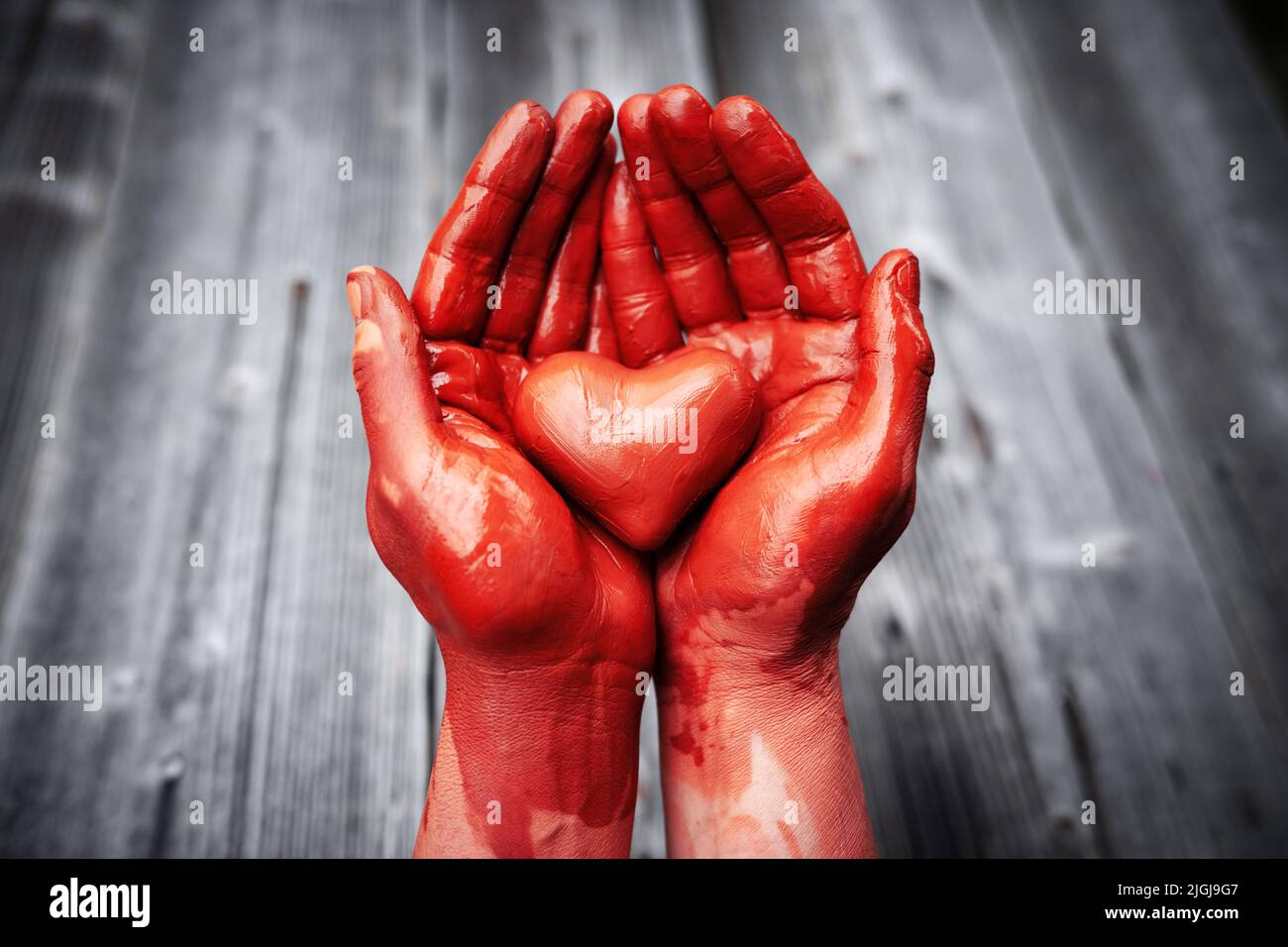 Heart made of blood colour potter's clay in the hands of a master potter. Love concept Stock Photo