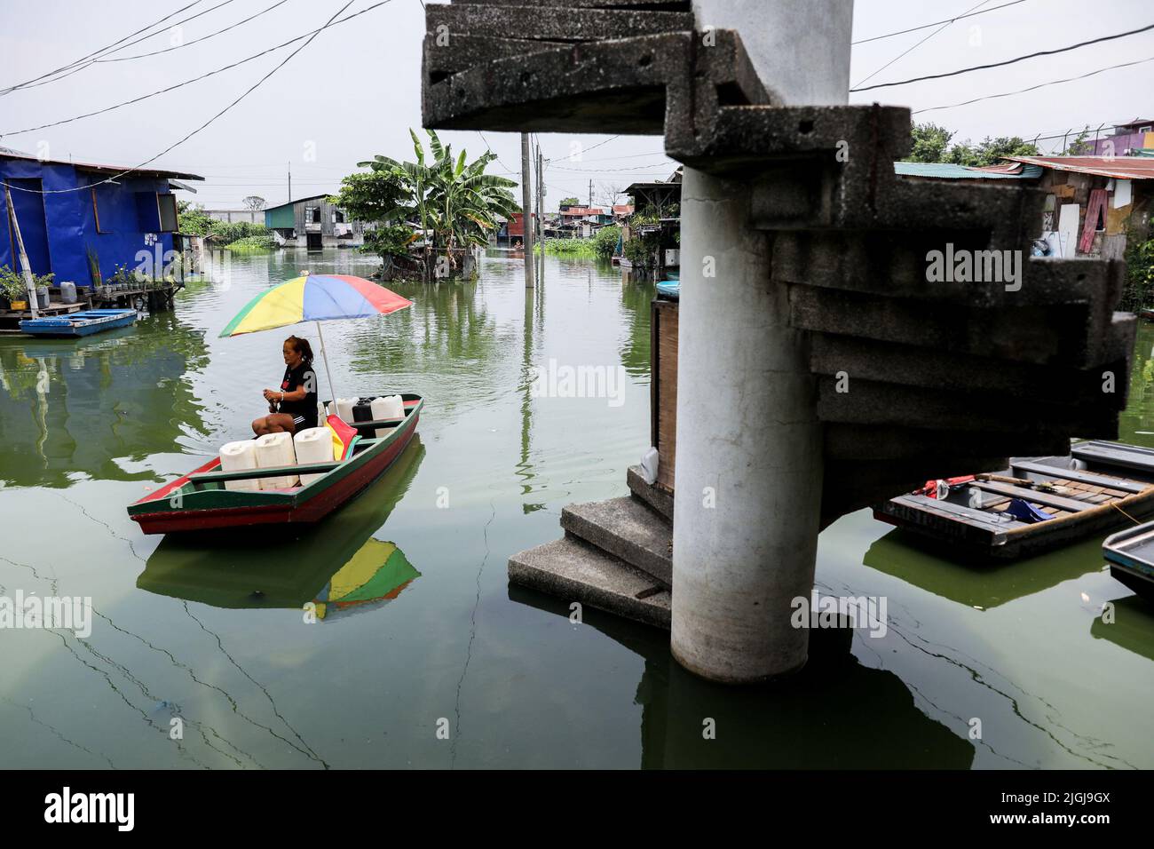 A woman paddles on stagnant floodwaters  inside the Artex Compound in Malabon, Metro Manila. The village has been flooded by stagnant waters for several years. The inhabitants, who are mostly poor, have to use boats for their daily mode of transportation, and even visiting their neighbors has become a tedious effort. In order to get access to basic necessities like groceries, residents need transport to other parts of the city that are not flooded. One of the biggest problems for the residents living in the area is getting clean water for day-to-day life. Philippines. Stock Photo