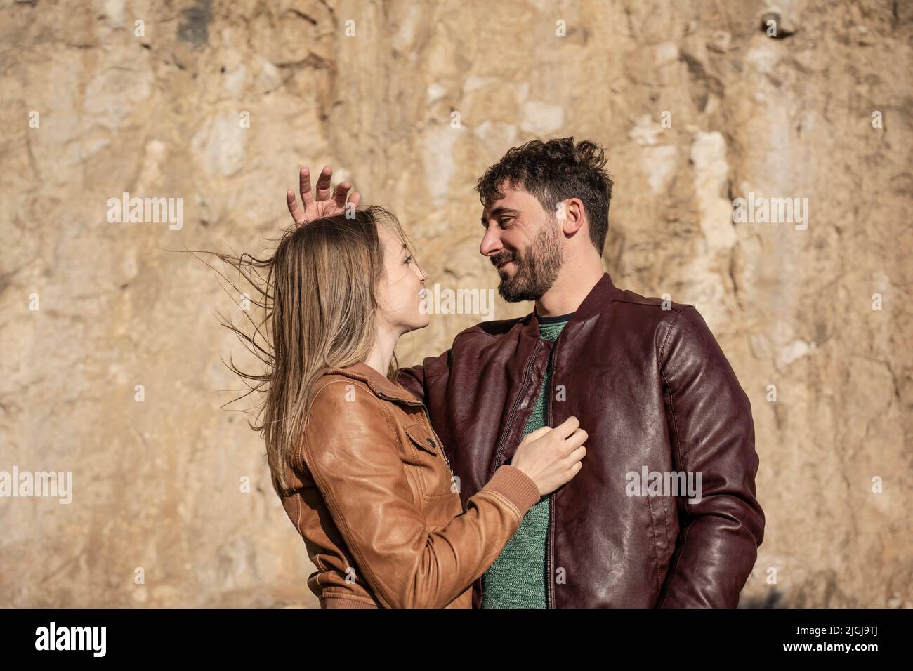 Couple of travelers looking each other eyes at sunset while the man