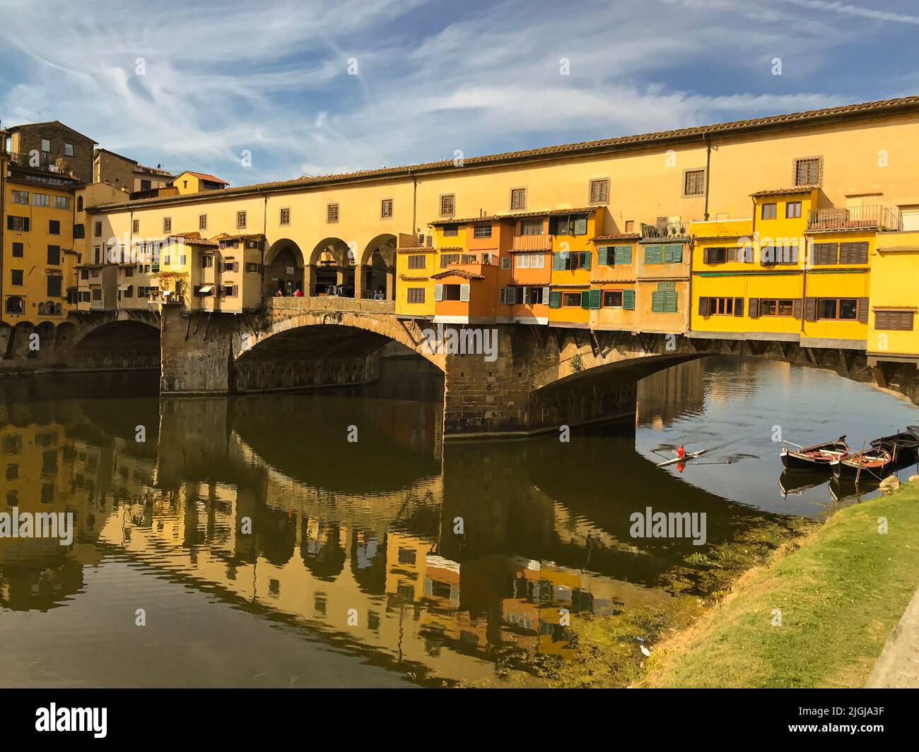 View of the Ponte Vecchio - Old Bridge - in Florence (Firenze) - by the river Arno with blue sky and reflections in the water. Famous landmark in Tusc Stock Photo