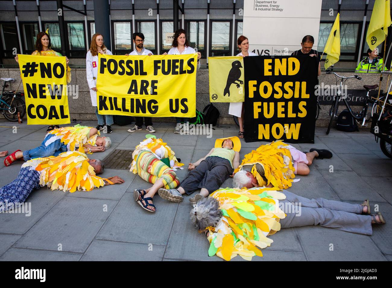London, UK. 11th July, 2022. Climate activists from Extinction Rebellion dressed as canaries stage a Stop Coal die-in outside the Department for Business, Energy and Industrial Strategy (BEIS). The activists are calling for no licences or planning consents to be granted for coal extraction by the Coal Authority, an executive non-departmental public body sponsored by BEIS, anywhere in the UK. Credit: Mark Kerrison/Alamy Live News Stock Photo