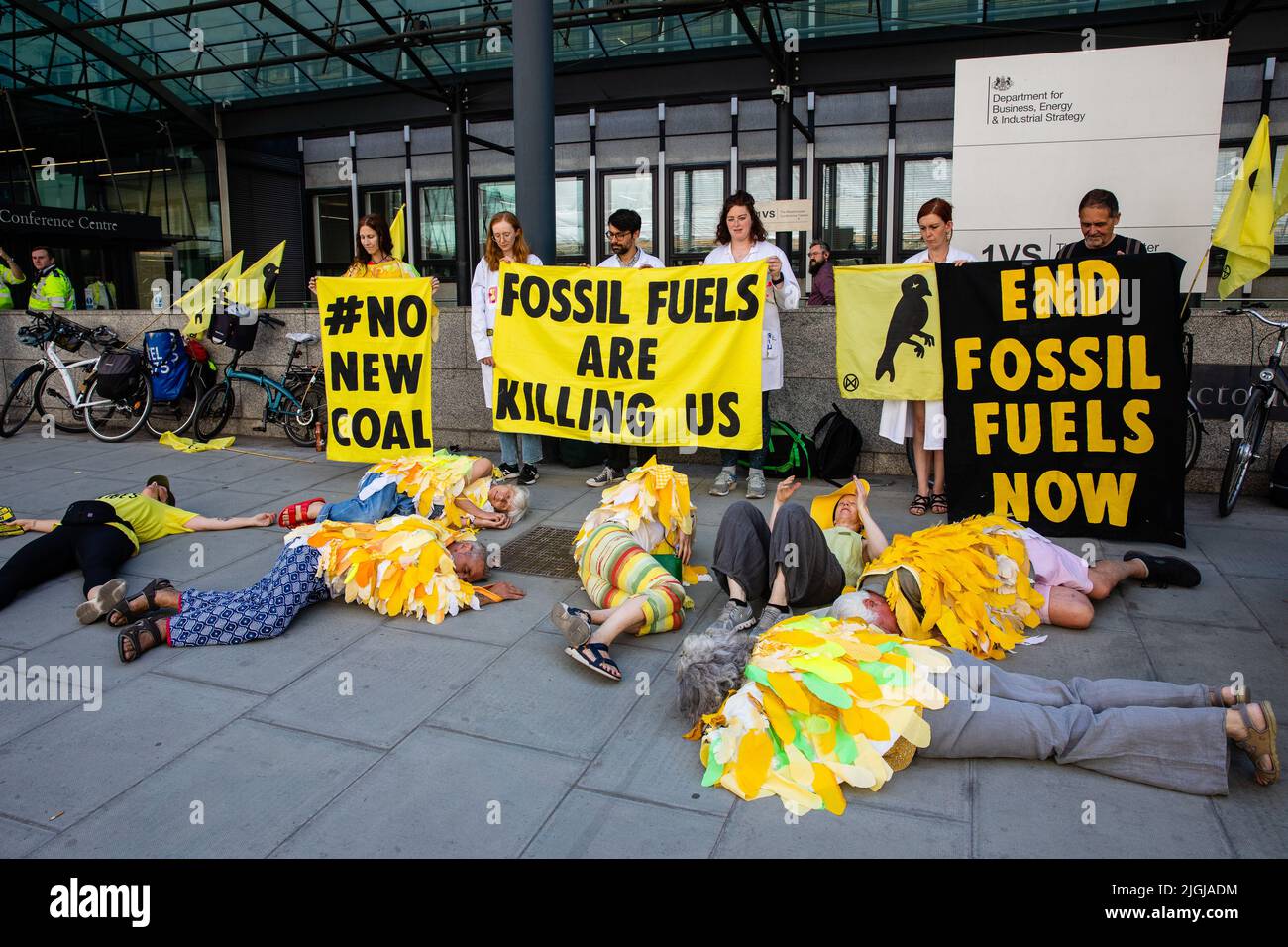 London, UK. 11th July, 2022. Climate activists from Extinction Rebellion dressed as canaries stage a Stop Coal die-in outside the Department for Business, Energy and Industrial Strategy (BEIS). The activists are calling for no licences or planning consents to be granted for coal extraction by the Coal Authority, an executive non-departmental public body sponsored by BEIS, anywhere in the UK. Credit: Mark Kerrison/Alamy Live News Stock Photo