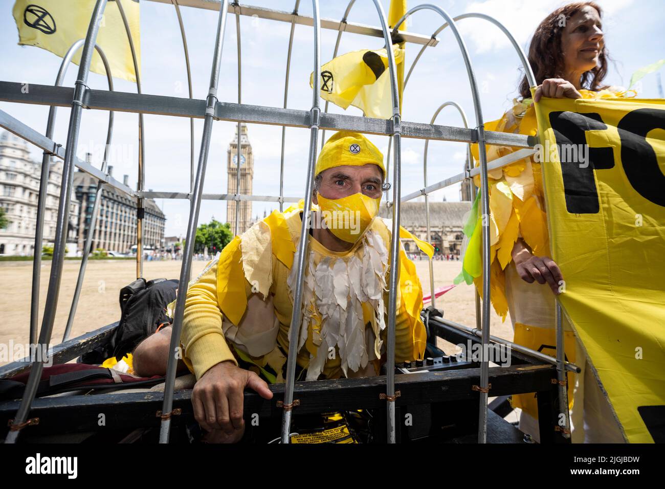 London, UK.  11 July 2022.  One of several members of Extinction Rebellion (XR), dressed as canaries in a coal mine, take part in a protest in Parliament Square calling for a stop to new coal mines in the UK. Credit: Stephen Chung / Alamy Live News Stock Photo