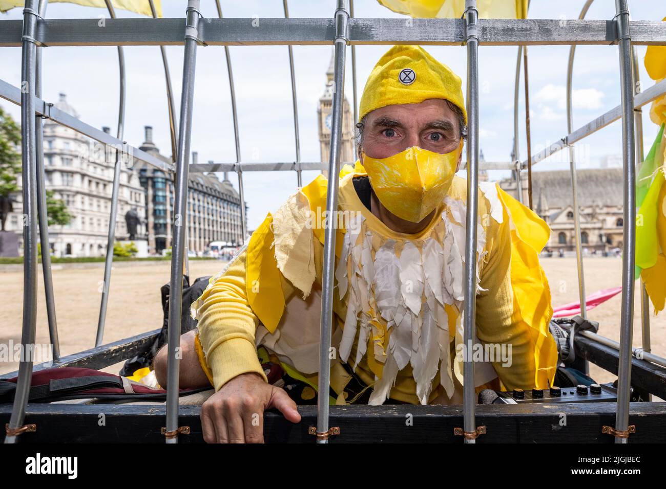 London, UK.  11 July 2022.  One of several members of Extinction Rebellion (XR), dressed as canaries in a coal mine, take part in a protest in Parliament Square calling for a stop to new coal mines in the UK. Credit: Stephen Chung / Alamy Live News Stock Photo