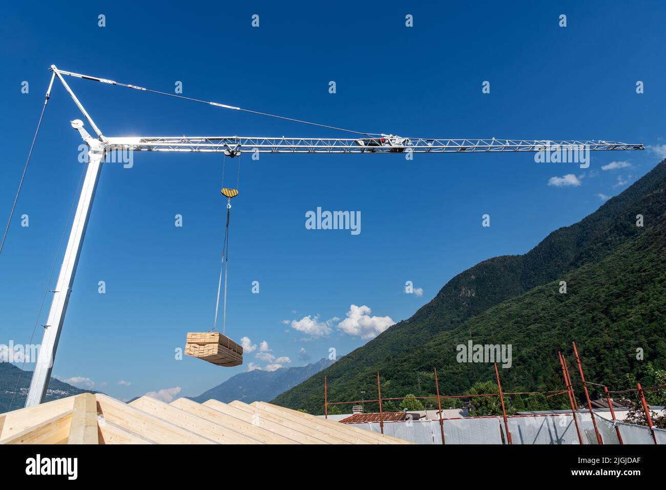 Construction crane  with hanging load of wood plank on a blue sky Stock Photo