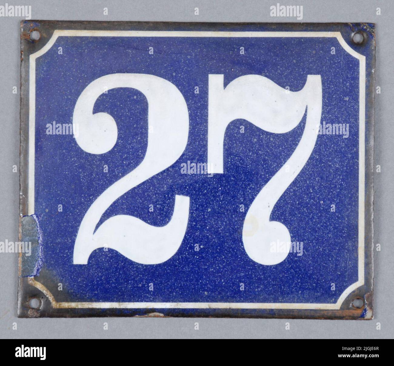 Gatunummerskylt Sign, street number sign of enamelled sheet metal. Rectangular. Blue with white frame and text '27'. Extremely black edge. Four holes for mounting. Greater enamel injury in the left. Respect 1970-02-07, when switching to a new sign. Stock Photo