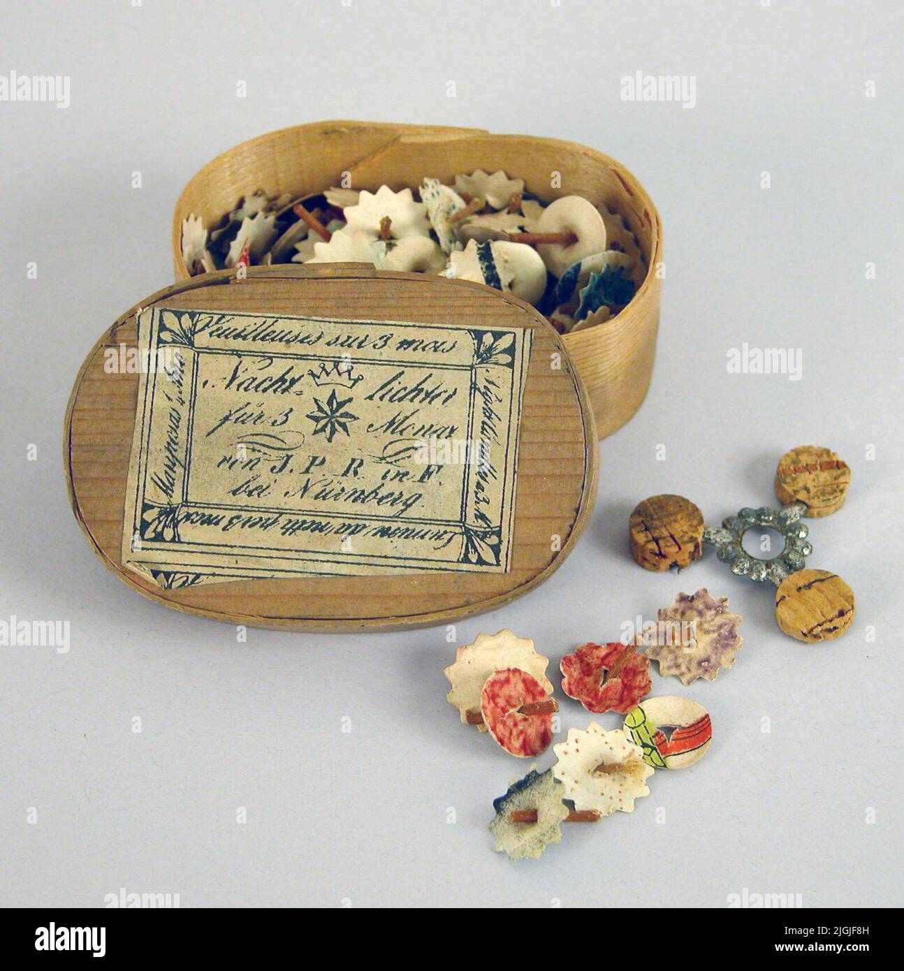 Nattljus Light, so -called. Night light. Oval box of shavings with paper label. In the box a variety of small wanders in round paper flowers in different colors and patterns. Float scaffolding metal and cork. The box's talent white with black handwritten text in different languages: 'Nachtlichter für 3 Menax von J.P.R. in F. Bei Nürnberg' etc. The wicks were placed in the float in a clay lamp or container filled with water and predatory oil. According to a label, they last for three months. Gift 1934 by Miss Ada Brolin, Karlskrona.Neg no: 92.120, 15 Stock Photo