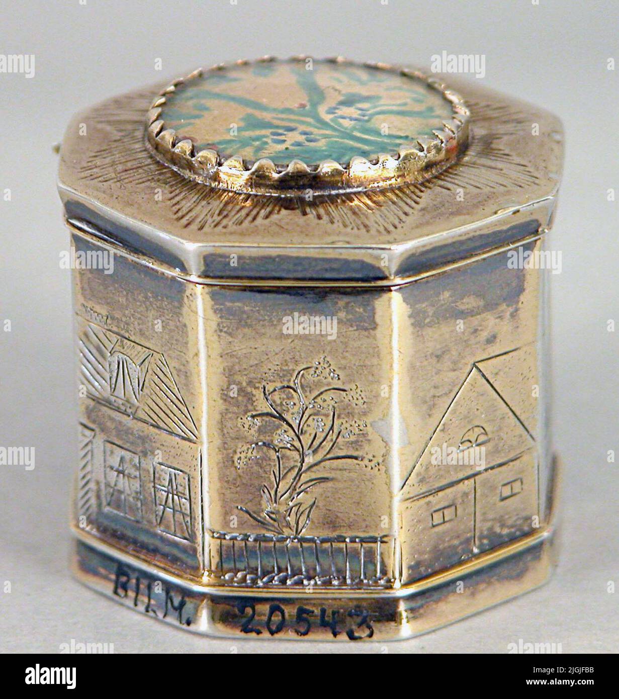 Dosa Odor box/mushroom box of gilded silver, made by Johan Wilhelm Hultgren, Karlskrona.åttkantig shape, lid with hinges. The lid with round flower painting under glass. The sides with engraved houses and trees. Stamped below the bottom; Manufacturer stamp JWH, control stamp, city weapon Karlskrona, year stamp G5. Engraved below the bottom; Hod.width over flats 31 cm. Testamentary Gift. Negative number: 95:91, 4. Literature: Bengtsson, Bengt Old Silver from Culture's collections. Västerås 1979. Stock Photo