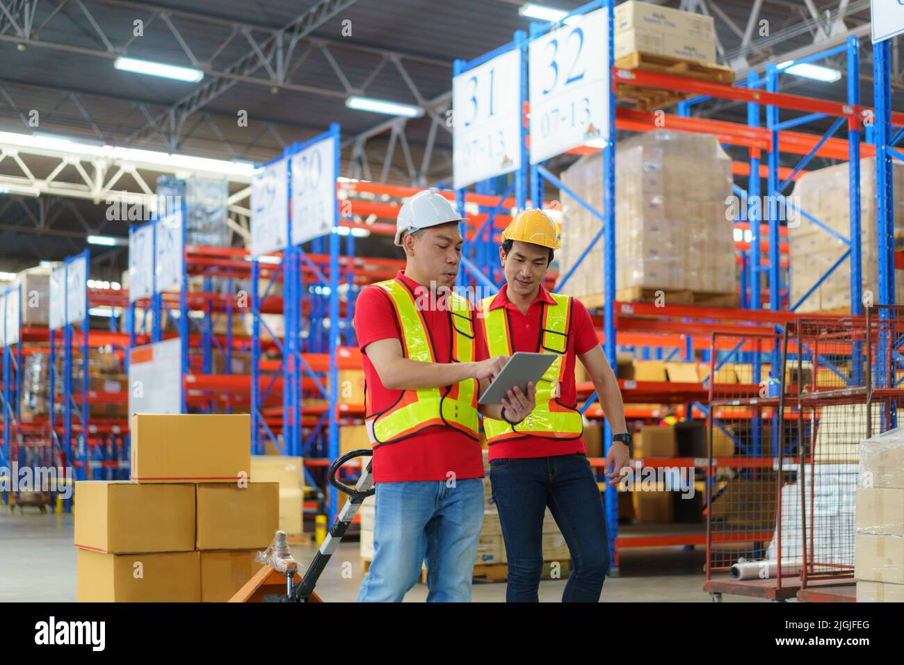 Asian man Warehouse worker talking with his foreman during unloading pallet shipment goods into a truck container, warehouse industry freight, logisti Stock Photo