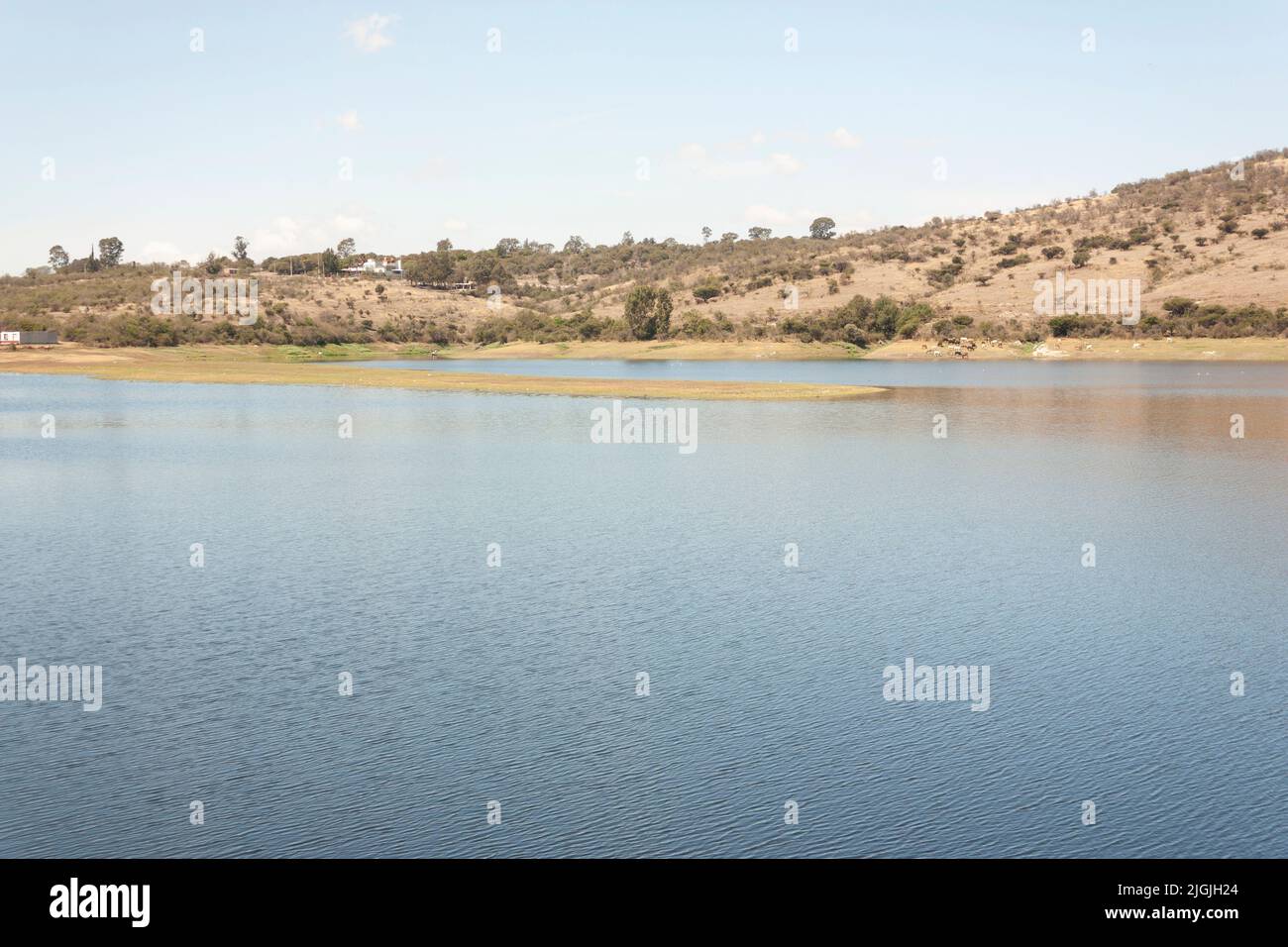 Outdoor body of water surrounded by land and blue sky with few clouds Stock Photo